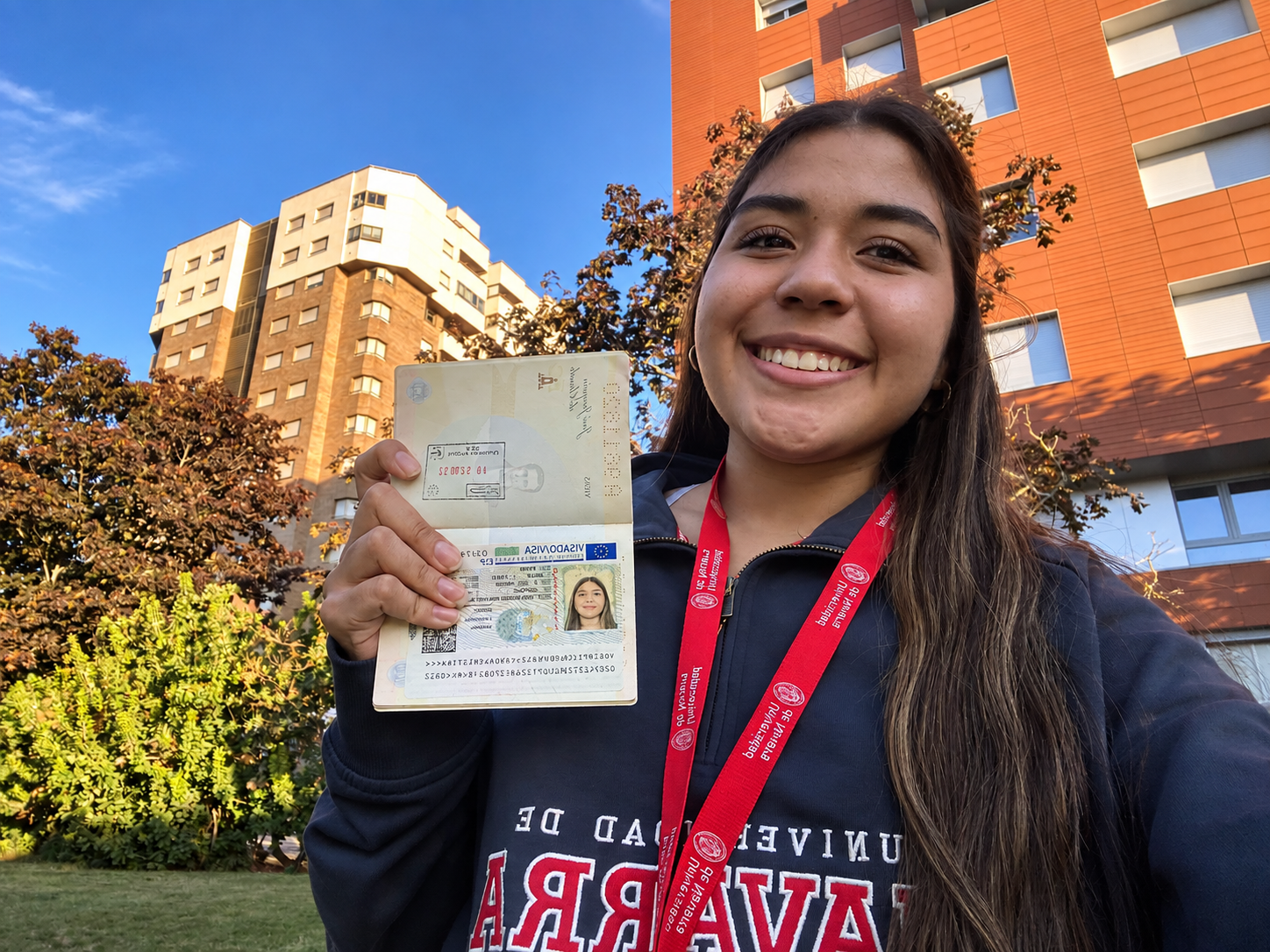 Anna afuera de su universidad en España mostrando su visa aprobada